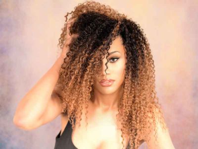 Model With Hand in Hair: Long Curly Sew In Hairstyle